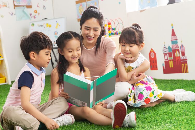 Asian teacher telling stories to a group of very young learners