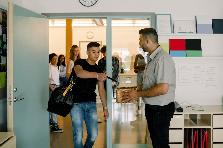 Secondary student showing a card to his teacher in the classroom