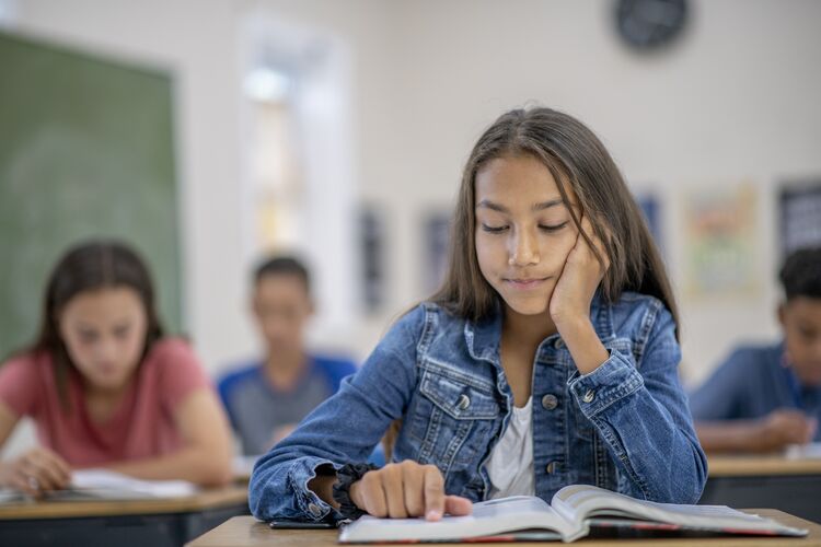 A young learner focussing on a book in class