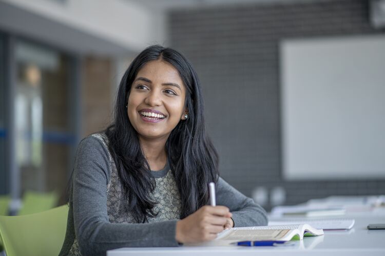 A young female Asian student smiling at a desk