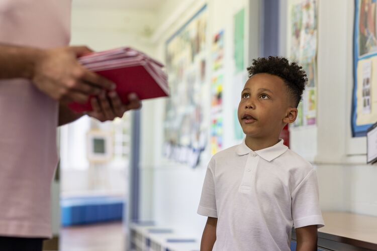 A primary school learner looking up at a teacher talking to him