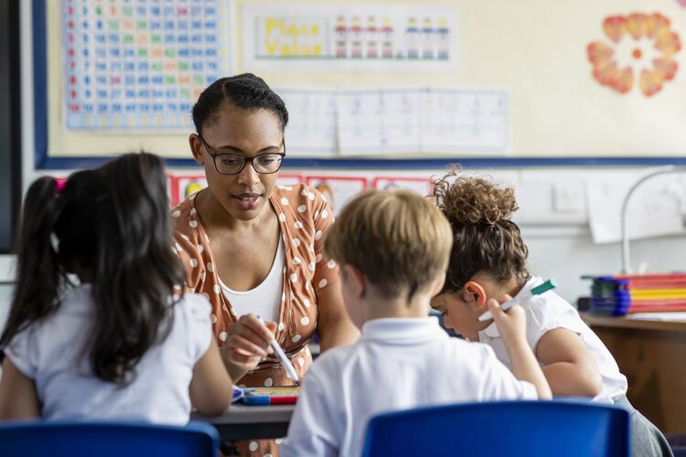 Teacher helping young children with reading in a classroom