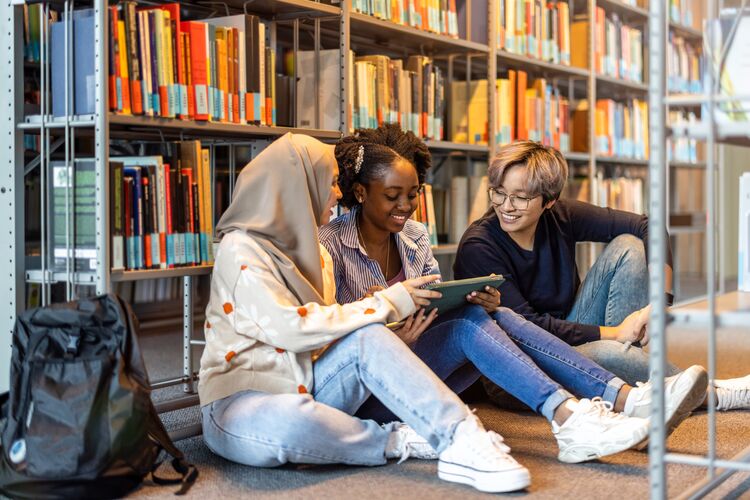 Group of diverse learners sitting in a library reading together