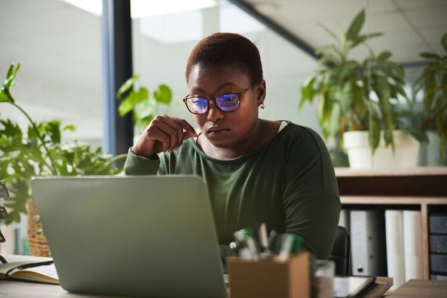 Black woman reading something on a computer and thinking