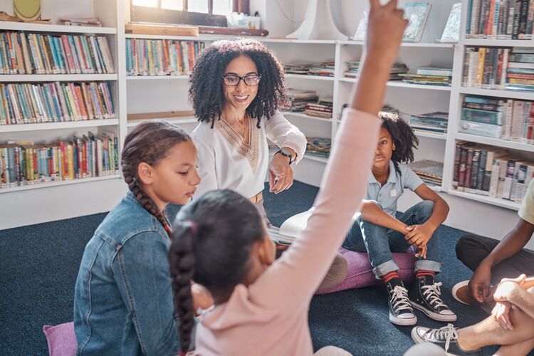 Group of young learners in a circle listening to their teacher