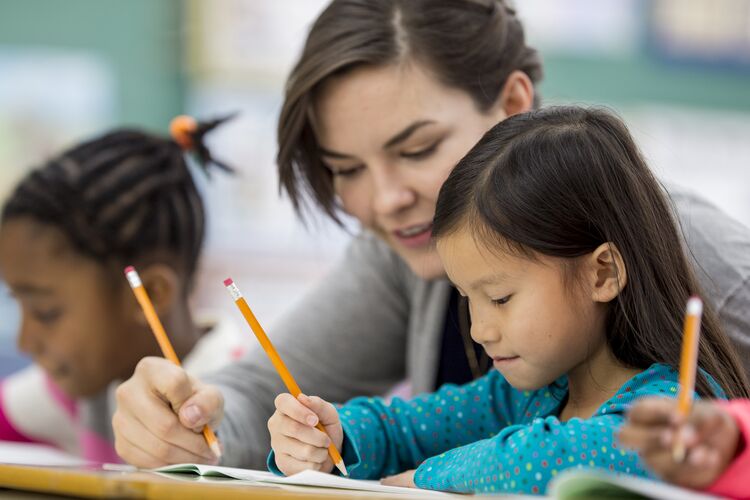 Ethnically diverse young learners learning to spell with their teacher