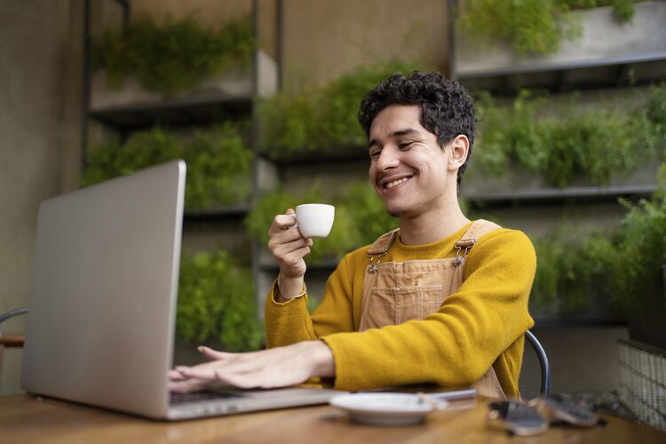 Young smiling man on a computer in a cafe