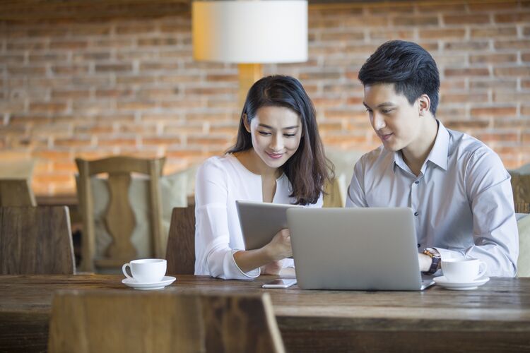 Woman and man in cafe using tablet and laptop together