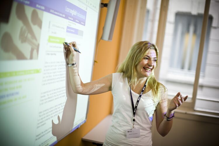 A teacher pointing to a sentence on an interactive whiteboard