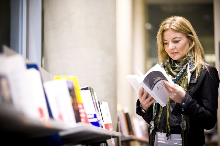 A woman in a library looking through a book