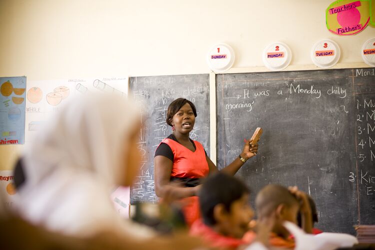 A teacher in Kenya standing in front of a blackboard