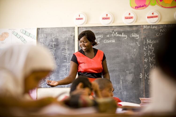 Teacher standing in front of a blackboard, addressing the class