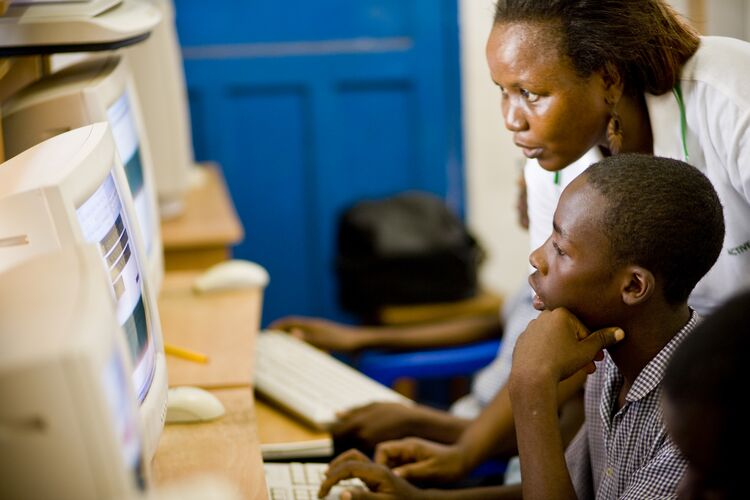 Pupil and teacher looking at computer screen