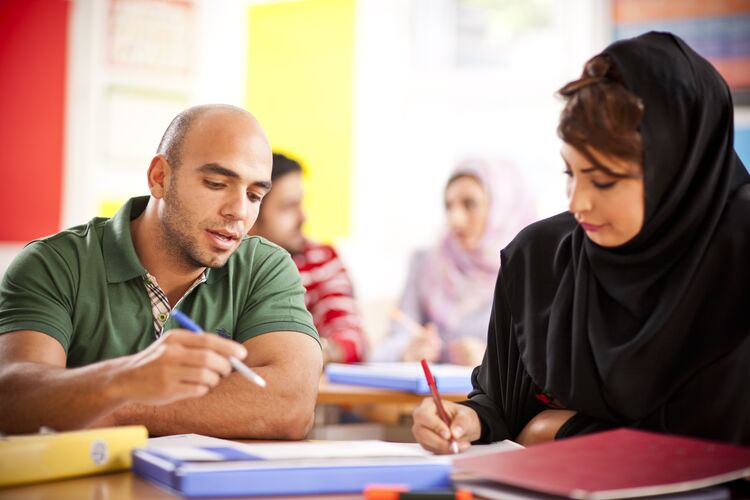 Two students talking together in a classroom