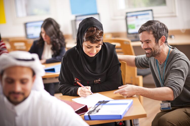 Teacher in Kuwait classroom next to a student taking a test