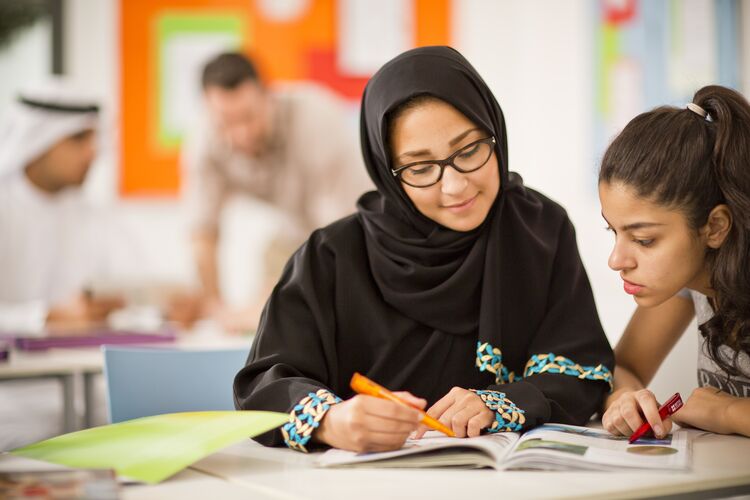 Teacher talking to student at a desk