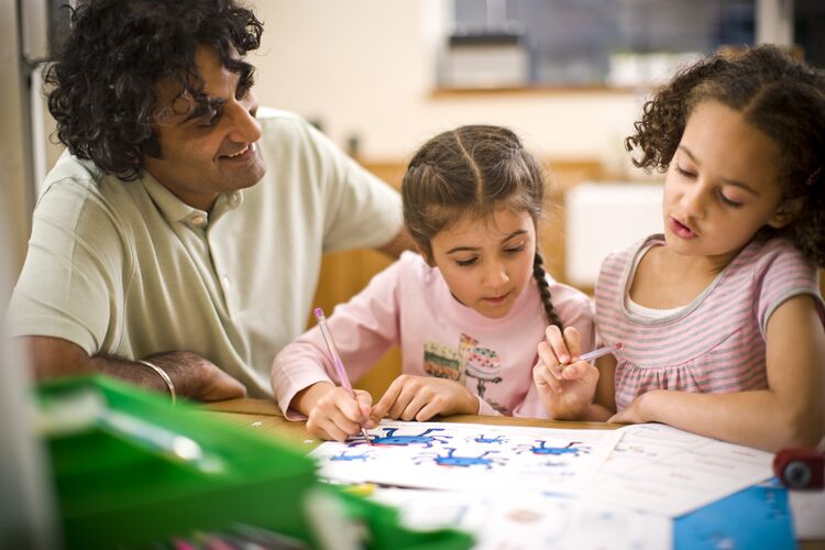 Father and 2 girls doing English homework and smiling