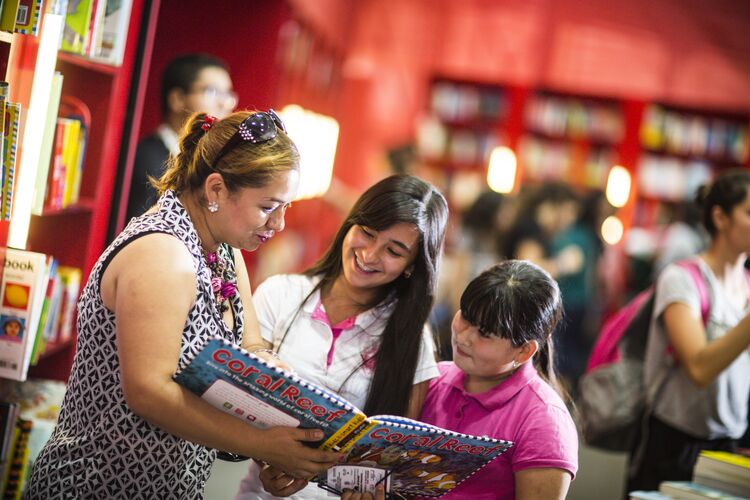 Two young learners and a teacher in Mexico reading a storybook together