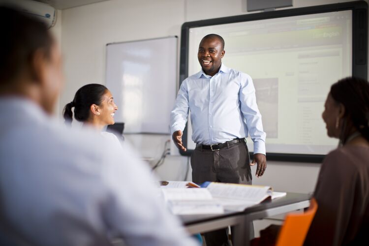 Teacher in Mozambique classroom laughing with students