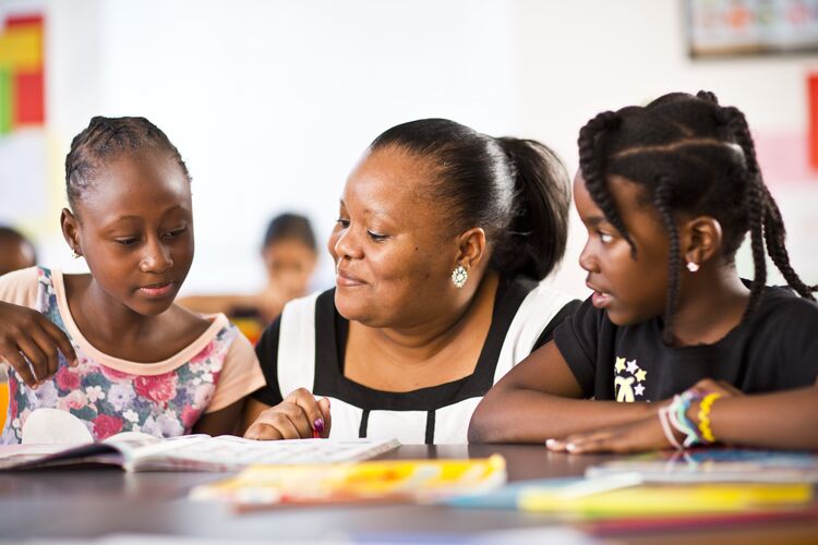 Teacher giving feedback to two young learners