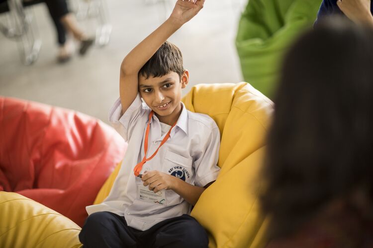 Young learner in Pakistan with his hand up in classroom