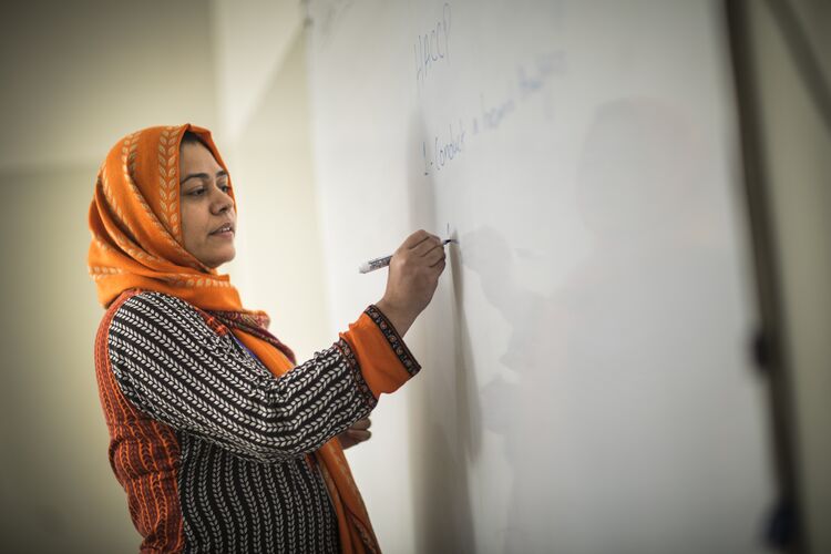 Teacher in Pakistan writing on whiteboard