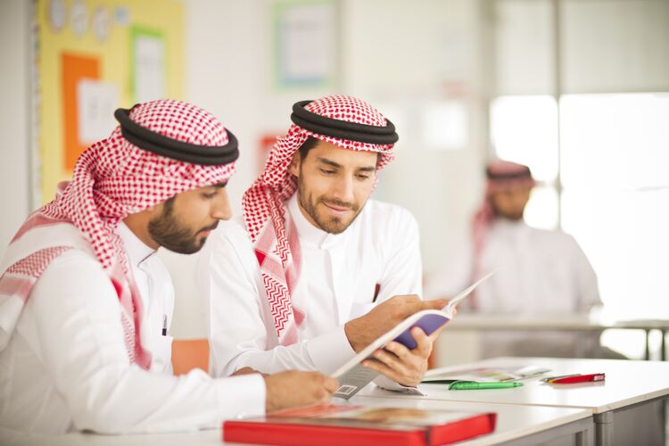 Students in Saudi Arabia looking at a textbook