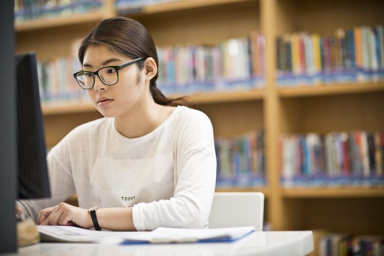 A student studying online in a library in Singapore