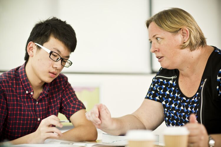 Teacher and student talking at a desk in a classroom in Singapore