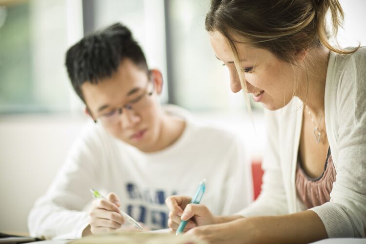 Two students looking at a textbook together