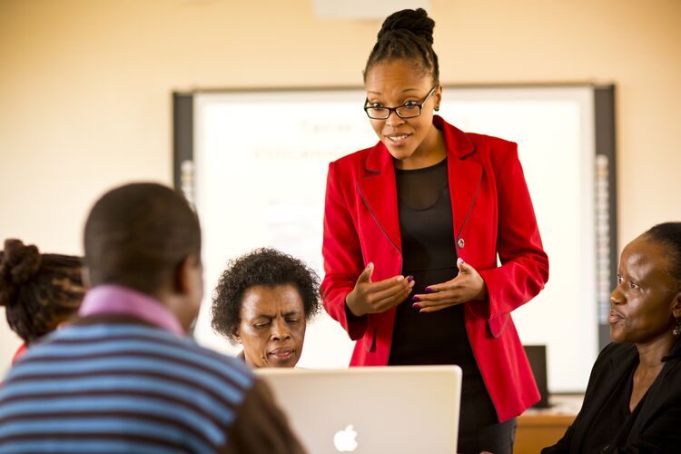 Teacher in South African classroom surrounded by adult learners