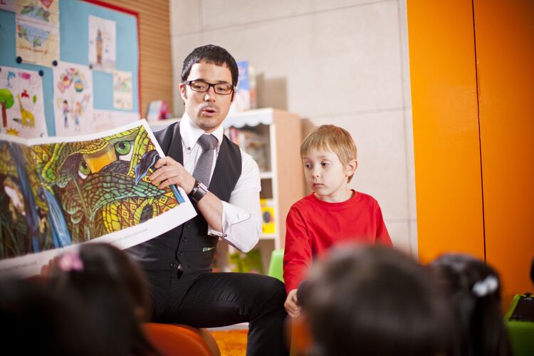 Male teacher in South Korea showing a picture book to learners