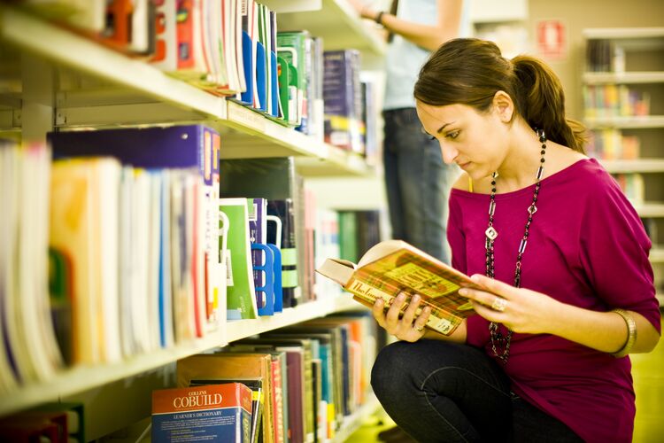 Student reading a book in a library