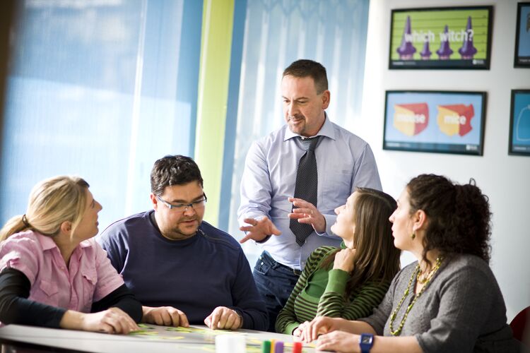 Students sitting at a table looking at a teacher