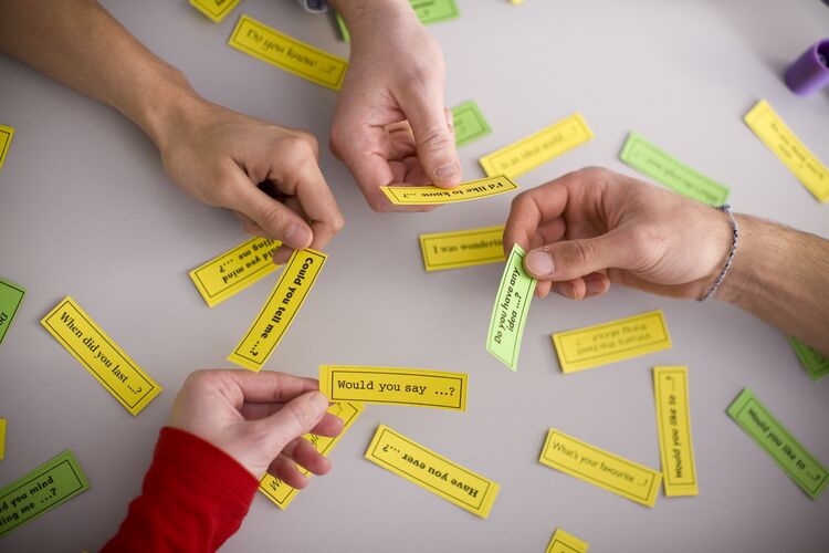 students hands playing a game with question cards