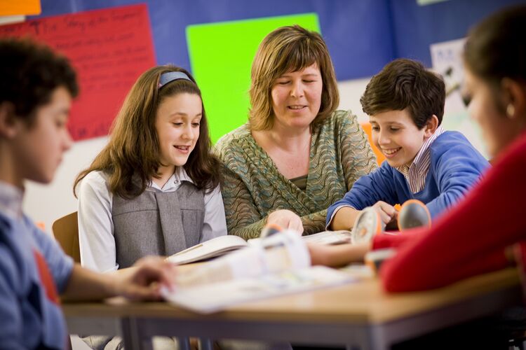 Teacher telling a story with students at a desk