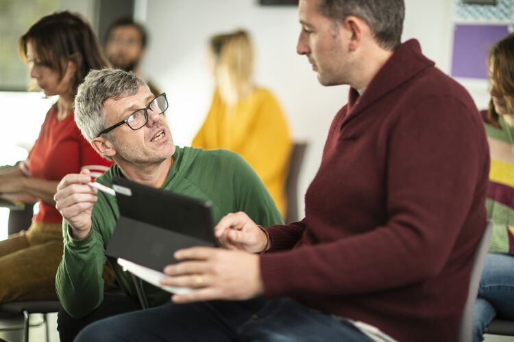 A teacher sitting next to a student giving them feedback