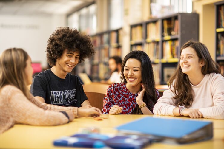 Four teenage students sitting around a table smiling