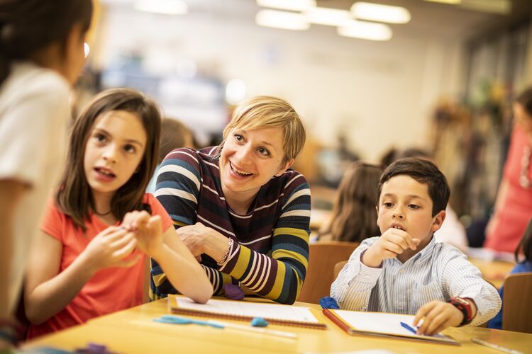 Teacher and young learners talking at a table