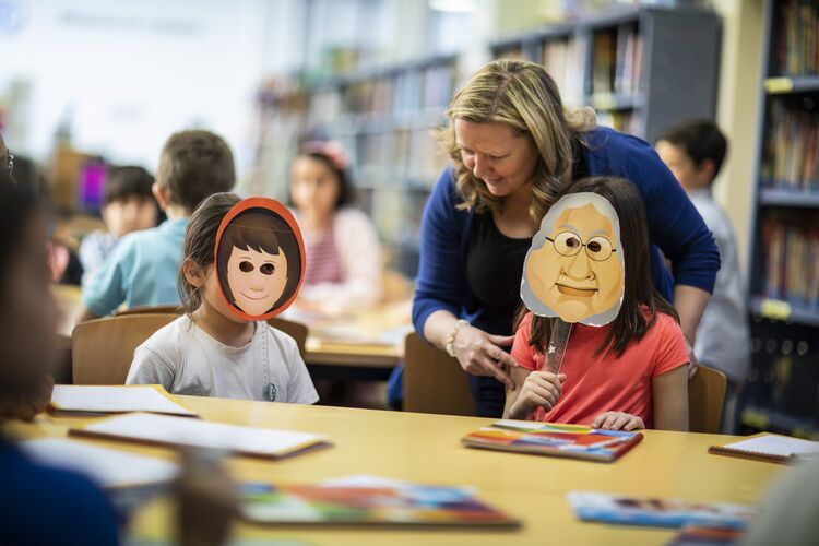 Two young students act out a story with masks