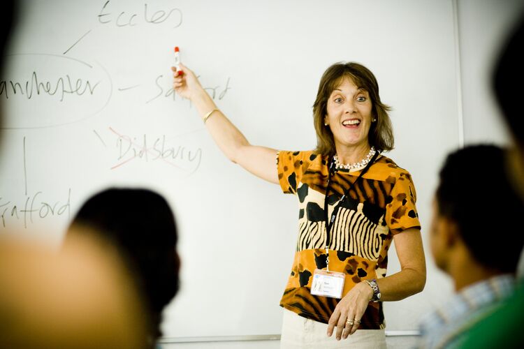 Teacher pointing at whiteboard in front of class