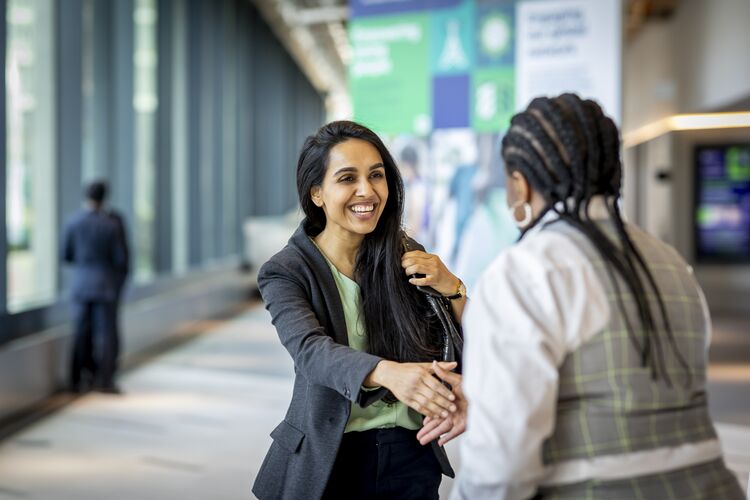 Two women shake hands in greeting