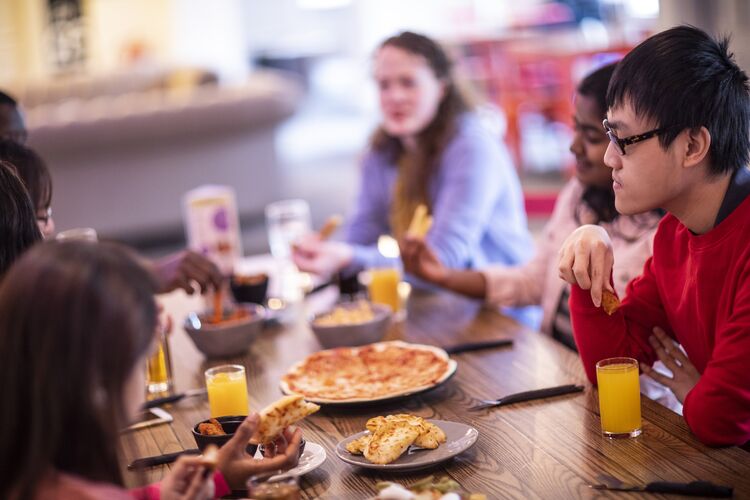 Group of students eating pizza together