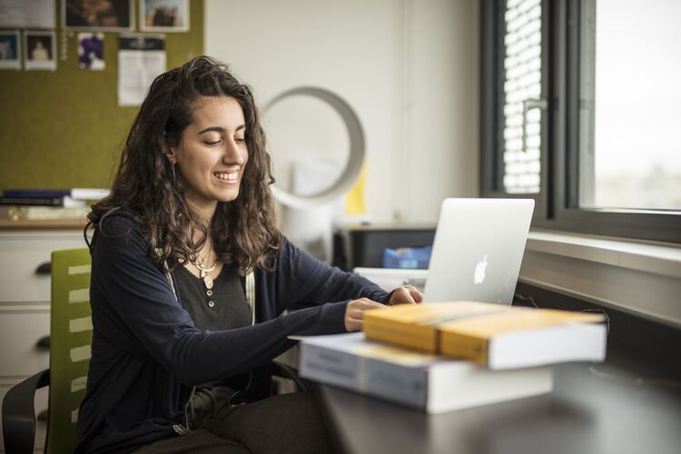 Girl studying at a laptop smiling