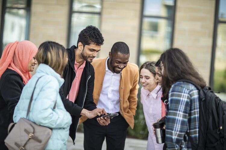 Group of students outside looking at a mobile phone