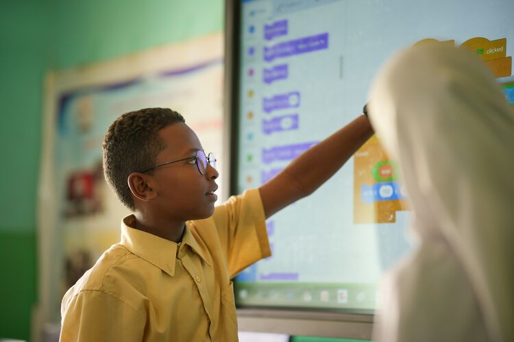 Student in Sudan pointing at words on Interactive whiteboard