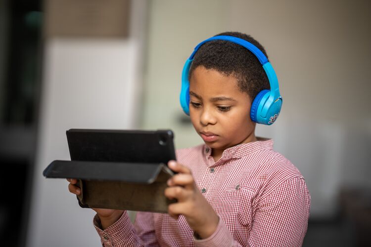 Student in Sudan listening to headphones with a tablet