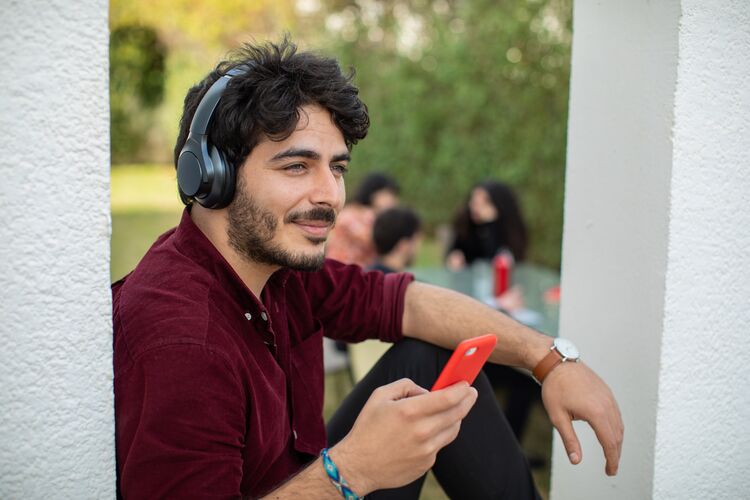 man with headphones using red mobile phone