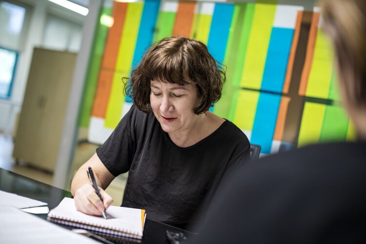 A woman writing a sentence on a notepad