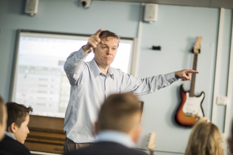 A teacher with a guitar in the classroom